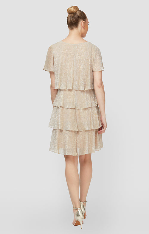 Woman wearing a gold tiered dress on a white background