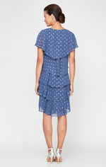 Woman wearing a blue tiered dress with white polka dots on a white background
